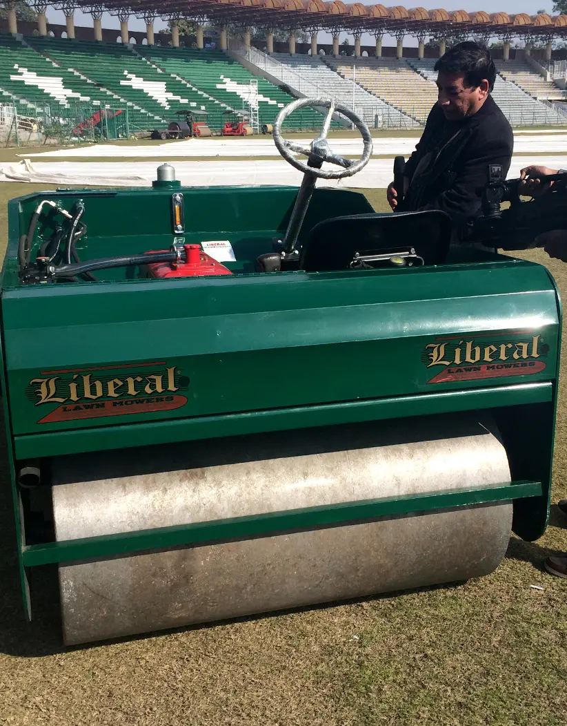 A modern, green Liberal automatic cricket roller is seen compacting the main pitch square at a major PCB cricket venue, undergoing final performance trials before its international export.