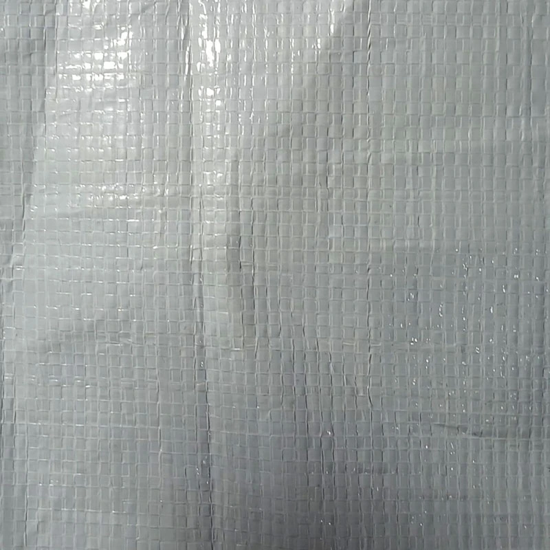 Durable grey woven polyethylene cricket pitch cover spread over a cricket wicket to protect against rain on a sports ground in Pakistan.